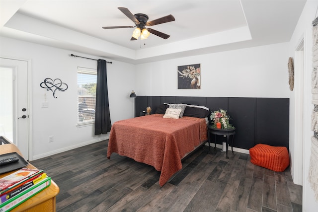 bedroom with dark wood-style floors, a raised ceiling, and baseboards