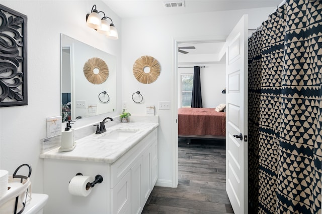 ensuite bathroom with toilet, visible vents, vanity, wood finished floors, and ensuite bathroom