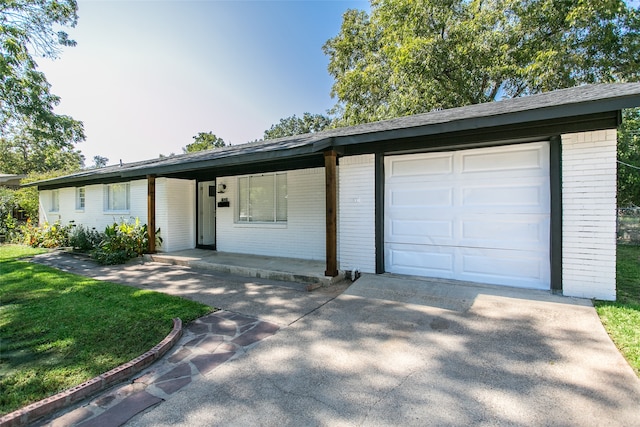 ranch-style house featuring covered porch, a front lawn, and a garage