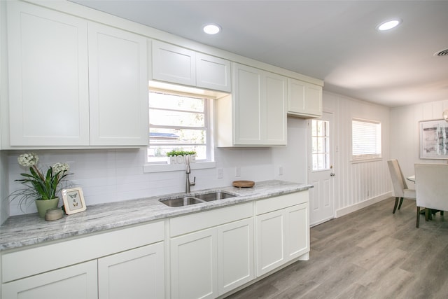 kitchen with plenty of natural light, white cabinets, sink, and light wood-type flooring