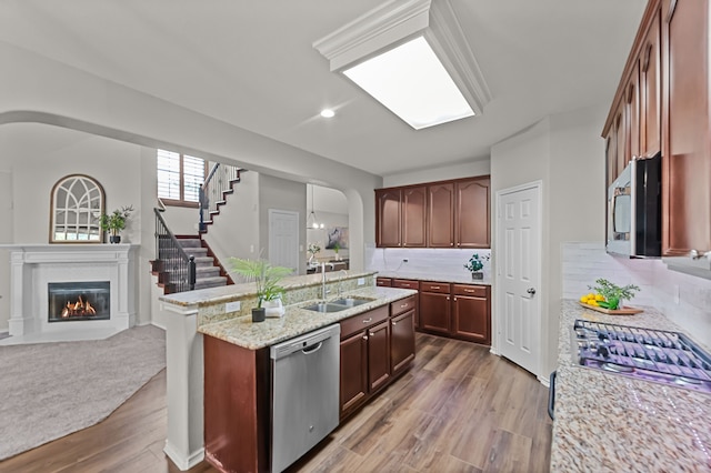 kitchen featuring sink, stainless steel appliances, backsplash, hardwood / wood-style floors, and an island with sink