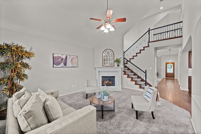 living room featuring a towering ceiling, hardwood / wood-style flooring, and ceiling fan