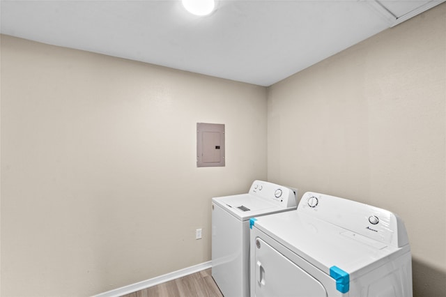 washroom with electric panel, washing machine and dryer, and light wood-type flooring