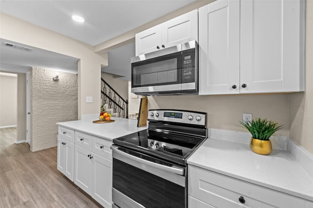 kitchen with stainless steel appliances, light hardwood / wood-style flooring, and white cabinets