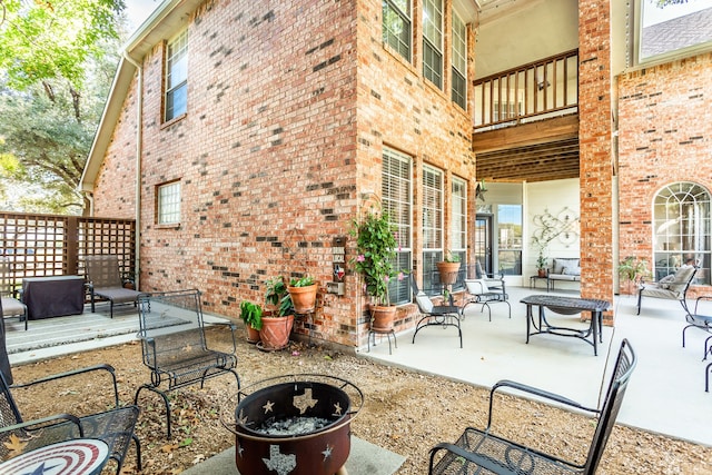 view of patio featuring an outdoor living space with a fire pit and a balcony