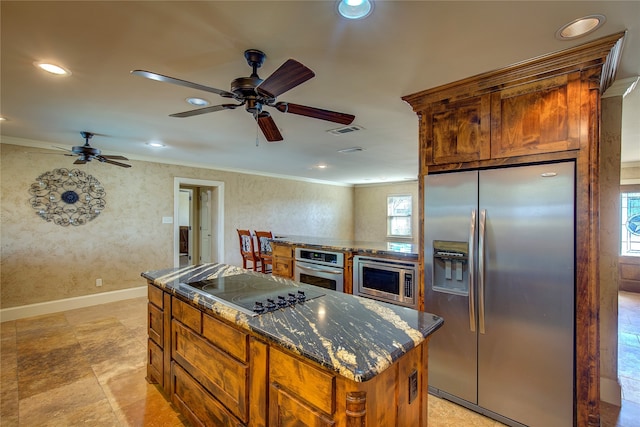 kitchen with dark stone countertops, stainless steel appliances, plenty of natural light, and a kitchen island