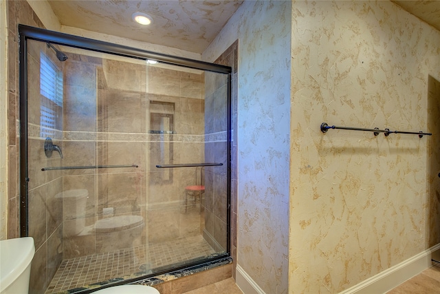 bathroom with a shower with door and toilet