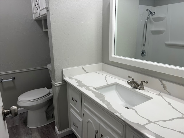 bathroom featuring vanity, hardwood / wood-style flooring, toilet, and a shower