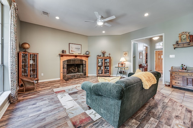 living room with ceiling fan, wood-type flooring, and a tile fireplace