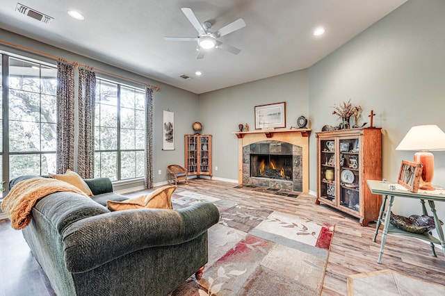 living room featuring ceiling fan, a fireplace, and light wood-type flooring