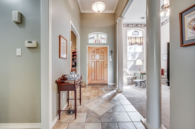 entrance foyer with ornate columns, crown molding, and light colored carpet