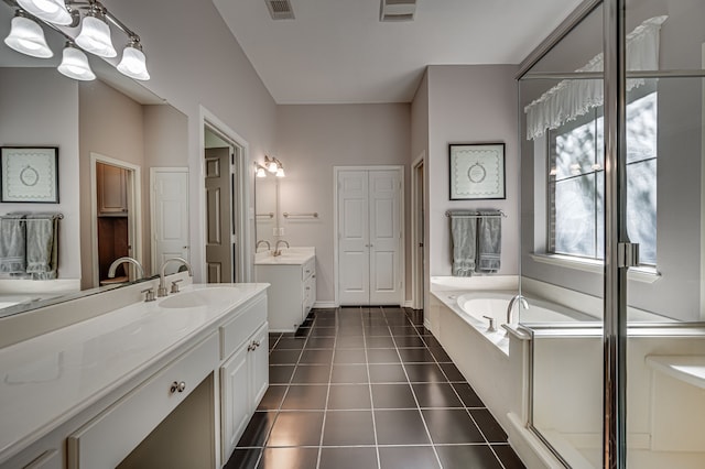 bathroom with tile patterned floors, vanity, and tiled tub