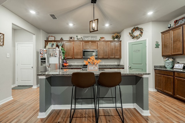 kitchen featuring appliances with stainless steel finishes, dark stone counters, and a kitchen island