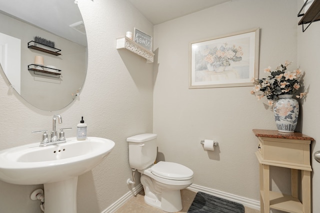 bathroom featuring toilet, tile patterned floors, and sink