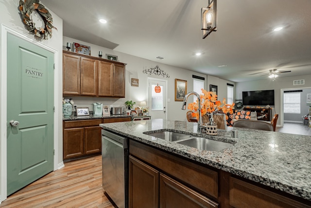 kitchen featuring ceiling fan, dishwasher, sink, light wood-type flooring, and light stone countertops