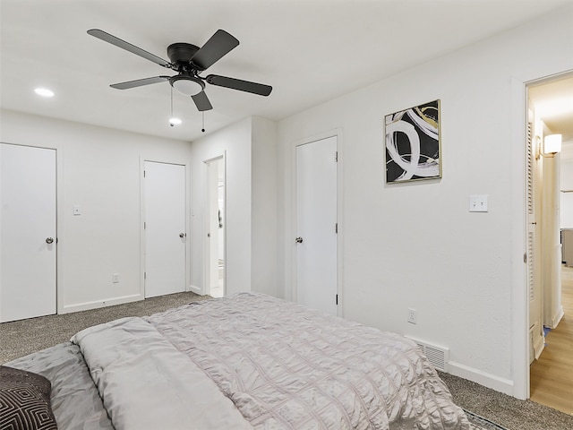 carpeted bedroom with two closets and ceiling fan