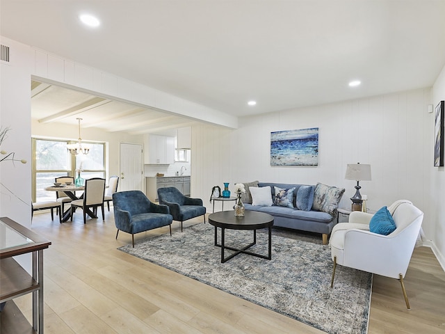 living room featuring an inviting chandelier, beamed ceiling, sink, and light hardwood / wood-style floors