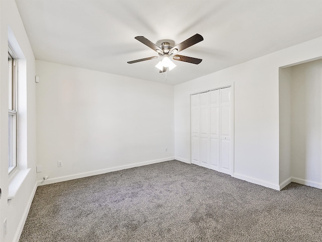 unfurnished bedroom with dark colored carpet, a closet, and ceiling fan