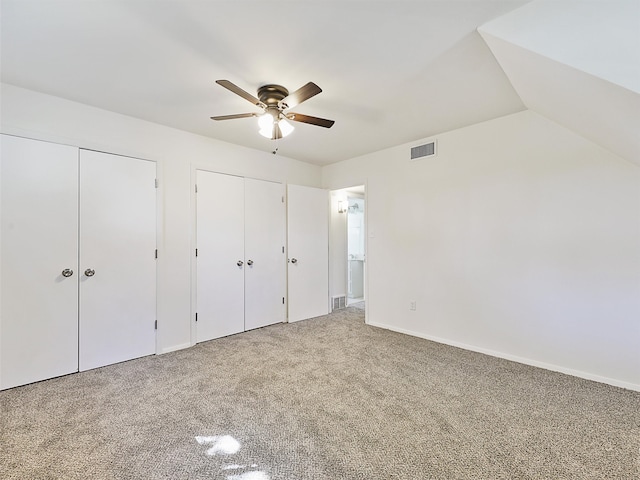 unfurnished bedroom with multiple closets, vaulted ceiling, carpet floors, and ceiling fan