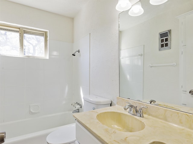 full bathroom featuring tiled shower / bath, vanity, and toilet