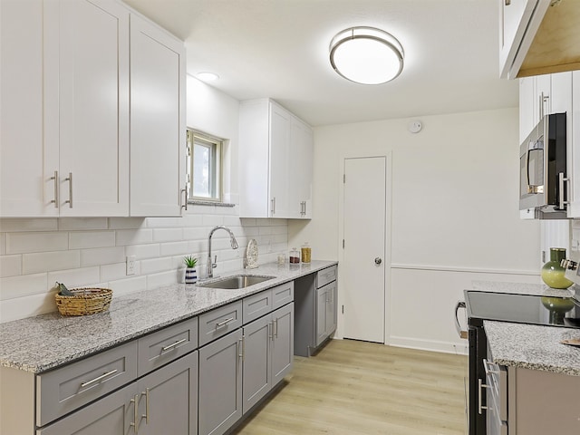 kitchen with light hardwood / wood-style floors, white cabinets, sink, and stainless steel appliances