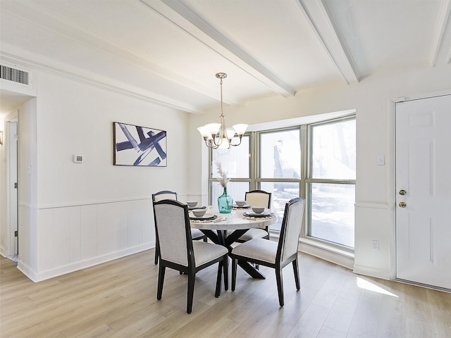 dining area with an inviting chandelier, beamed ceiling, and light wood-type flooring