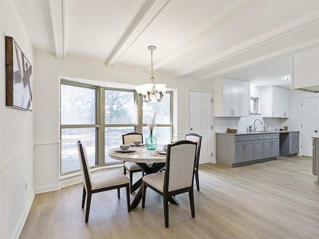 dining area featuring light hardwood / wood-style floors, an inviting chandelier, and beam ceiling