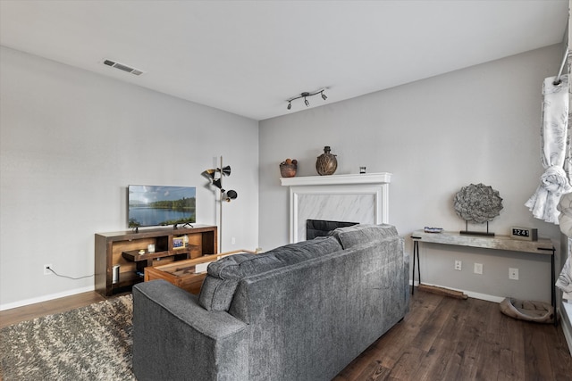 living room with rail lighting, a premium fireplace, and dark hardwood / wood-style floors