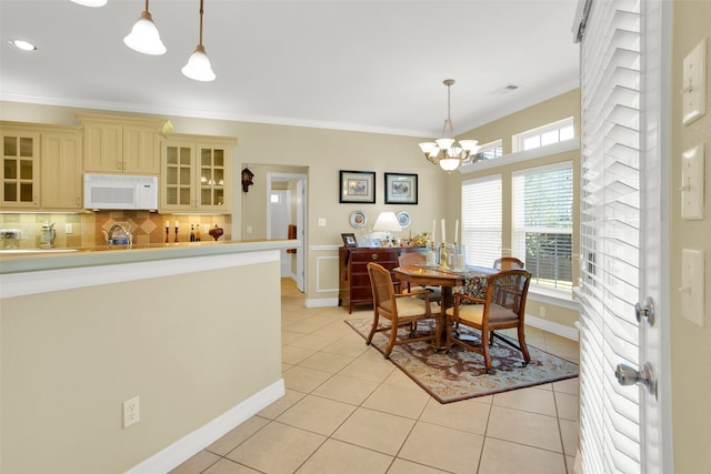 dining space featuring a notable chandelier, ornamental molding, and light tile patterned floors