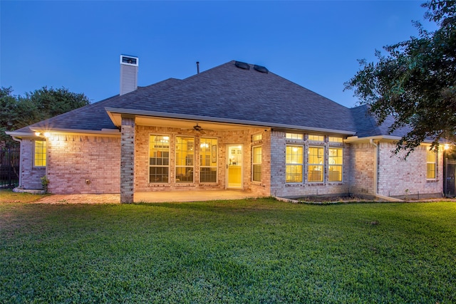 back house at dusk featuring a yard, a patio, and ceiling fan