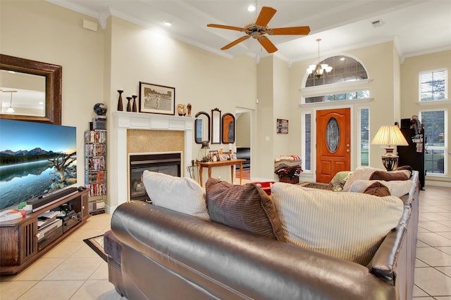 tiled living room with crown molding, a towering ceiling, and ceiling fan with notable chandelier