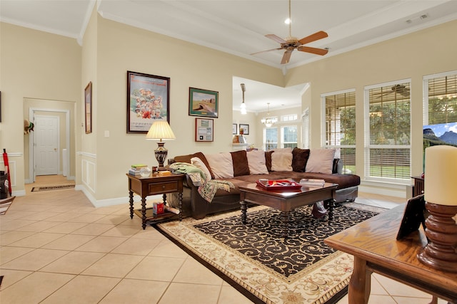 living room featuring ornamental molding, a high ceiling, ceiling fan with notable chandelier, and light tile patterned floors