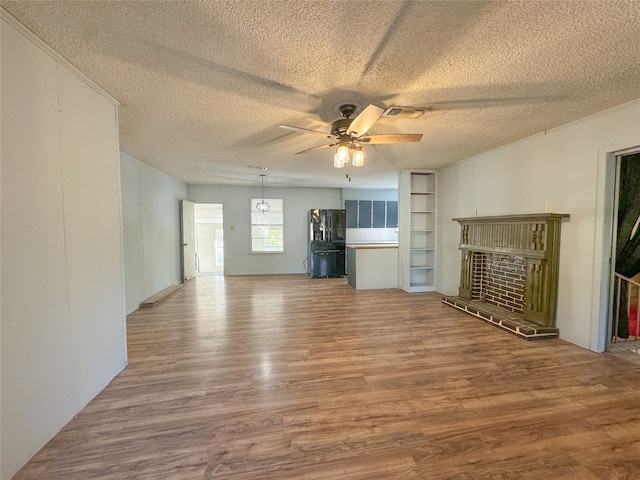 unfurnished living room with a textured ceiling, hardwood / wood-style flooring, a fireplace, and ceiling fan