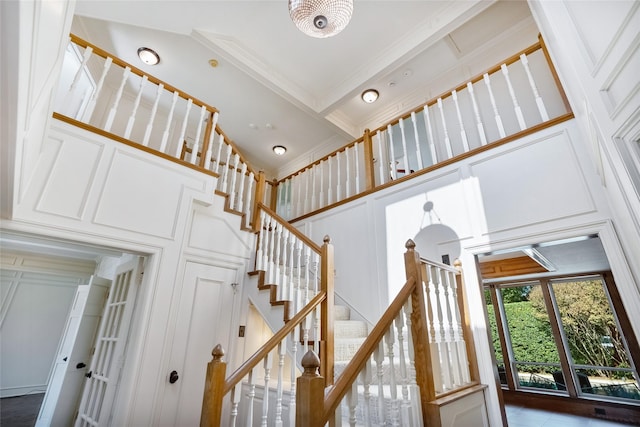 stairs featuring a towering ceiling and ornamental molding