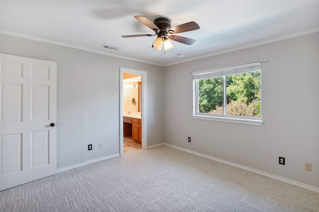 unfurnished bedroom featuring connected bathroom, light colored carpet, ceiling fan, and crown molding