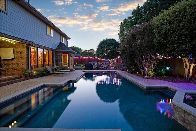 pool at dusk with a patio area