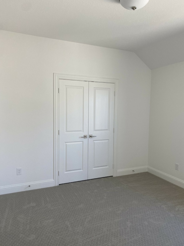 interior space with a closet, vaulted ceiling, and dark carpet