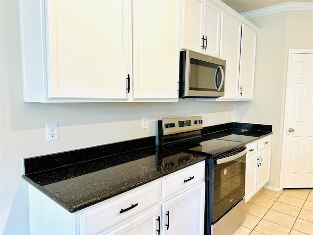 kitchen featuring crown molding, stainless steel appliances, light tile patterned floors, white cabinets, and dark stone countertops