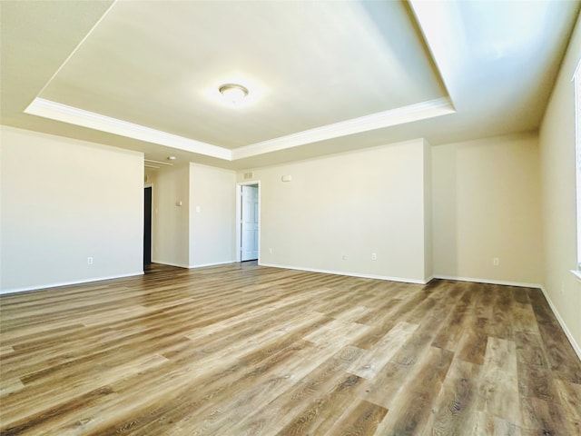 empty room with crown molding, hardwood / wood-style floors, and a raised ceiling