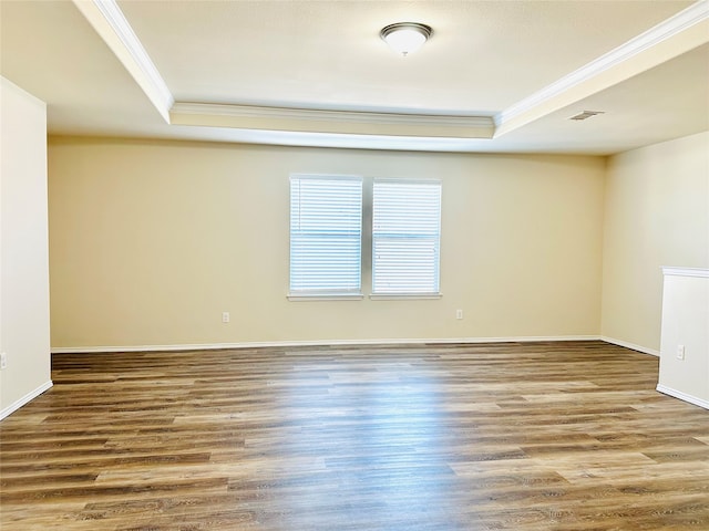 unfurnished room with wood-type flooring, a raised ceiling, and crown molding