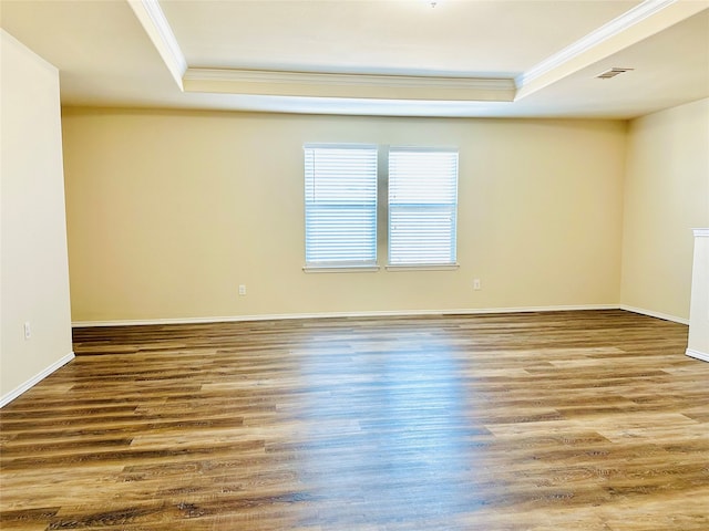 empty room featuring ornamental molding, wood-type flooring, and a raised ceiling