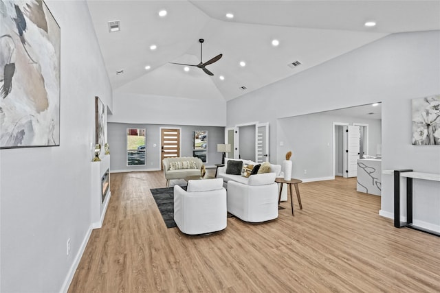 living room featuring ceiling fan, high vaulted ceiling, and light wood-type flooring