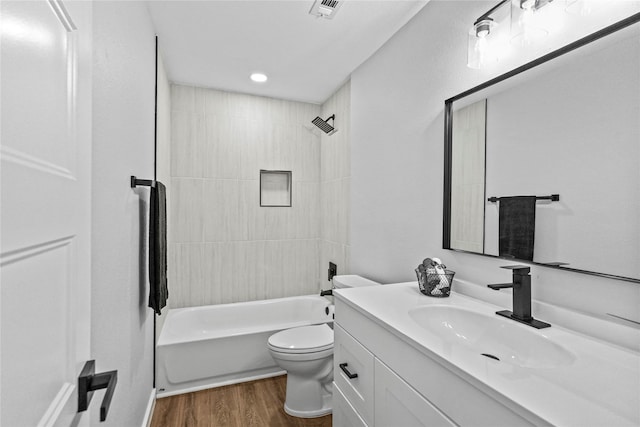 full bathroom with tiled shower / bath, vanity, wood-type flooring, and toilet