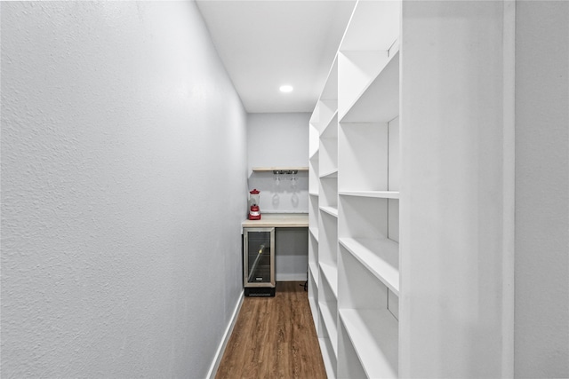 walk in closet with dark wood-type flooring and beverage cooler