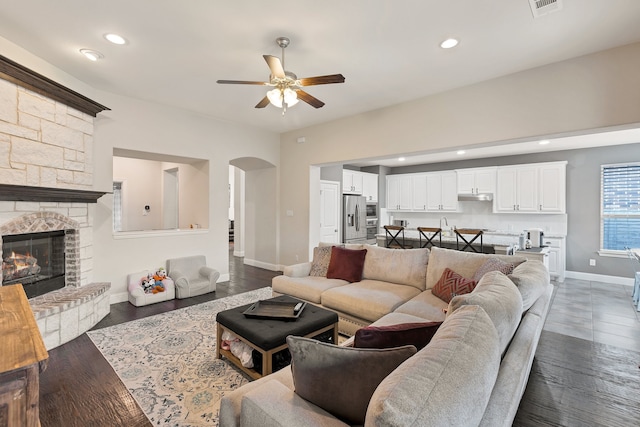 living room with a fireplace, dark hardwood / wood-style flooring, and ceiling fan