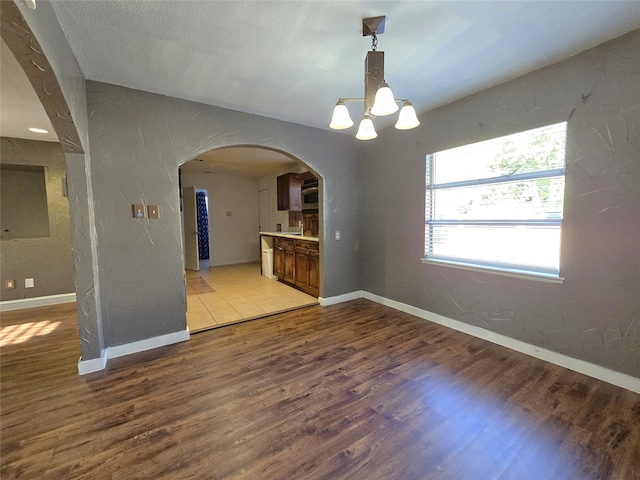 unfurnished dining area featuring hardwood / wood-style flooring and an inviting chandelier