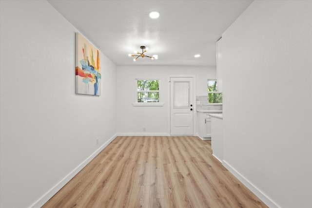 spare room featuring light wood-type flooring and a chandelier