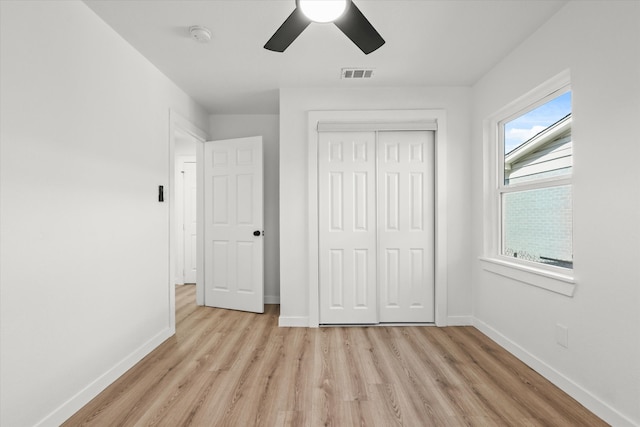 unfurnished bedroom featuring light wood-type flooring, ceiling fan, and a closet