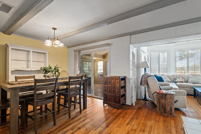 dining space with a notable chandelier, hardwood / wood-style flooring, and beamed ceiling