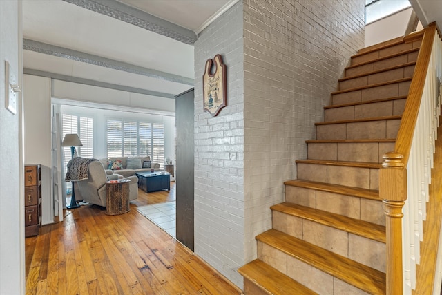 stairs with hardwood / wood-style floors and brick wall